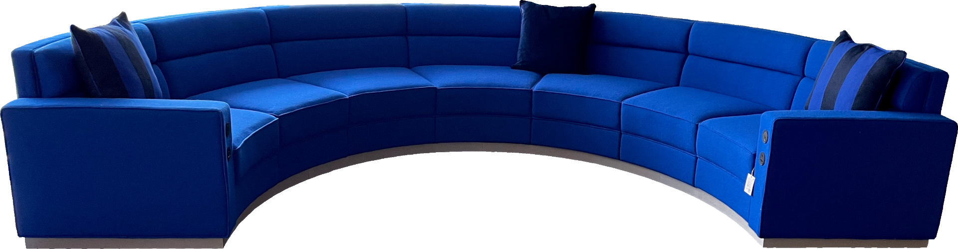 A large curved modular blue 7-seater sofa with fixed seat and back with plugs.