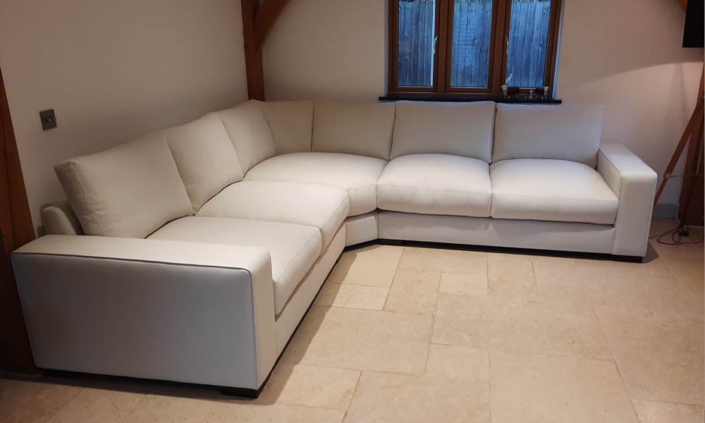 A white corner sofa with wide arms in the corner of a room.