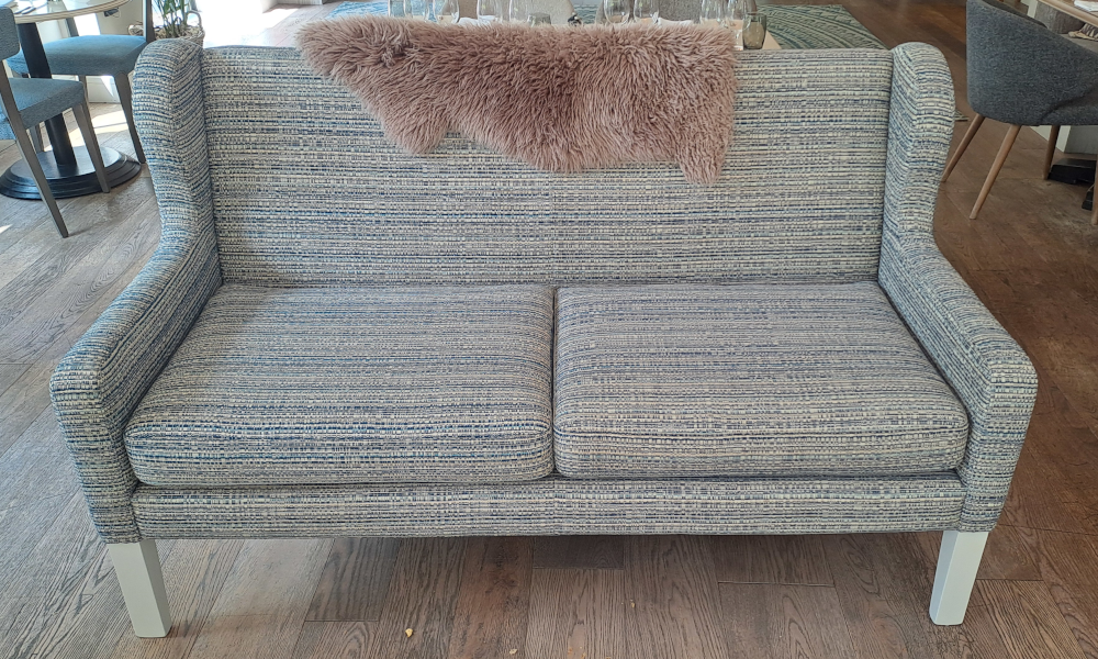 A gray 2-seater sofa with a wing back and removable seat cushions.