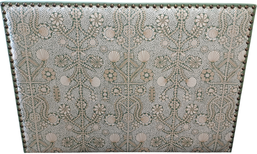 A king-sized headboard with decorative studs and a seashell pattern and contrast fabric.